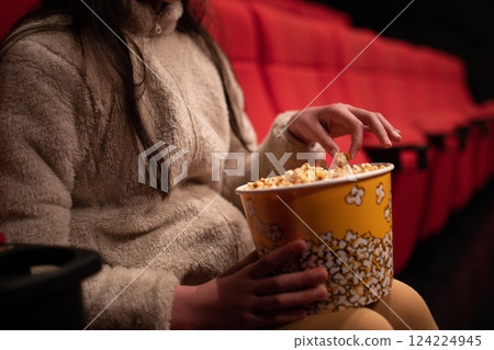 Girl eating popcorn and watching a movie 124224945