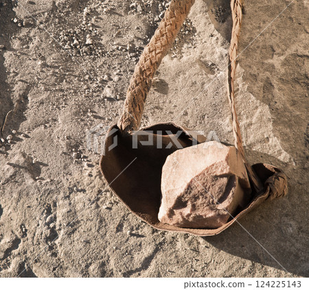 An antique leather sling lies on the ground An antique leather sling lies on the ground 124225143