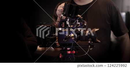 Film or video production setup with high end professional cinema cameras lighting camera rig and crew members working on set. Behind the scenes or BTS video shoot in a studio for cinematic visuals. 124225992