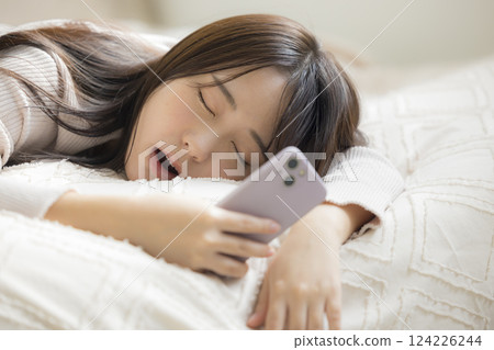 一名婦女在床上的看一個智能手機 一名婦女在床上的看一個智能手機 124226244