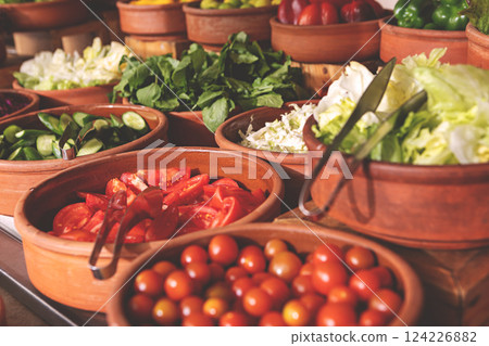 Delicious buffet table with Fresh and Vibrant Organic Vegetables in Rustic Clay Bowls and greens, featuring variety of healthy and colorful plant-based dishes for vegetarian or vegan meal 124226882