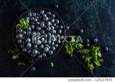 Blueberries in a black plate on a dark background. 124227655
