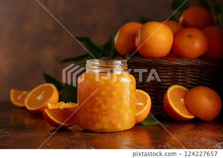 Orange jam and fresh fruits on a brown table. Orange jam and fresh fruits on a brown table. 124227657
