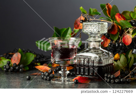 Black chokeberry juice and fresh berries on a black background. 124227669