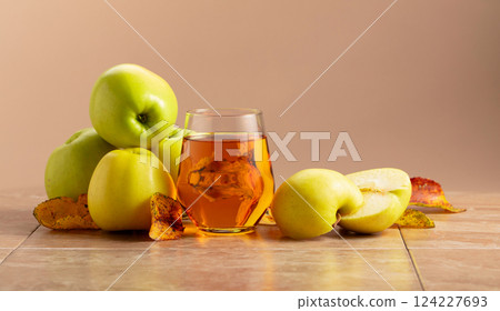 Apple juice and ripe apples with dried-up leaves. 124227693