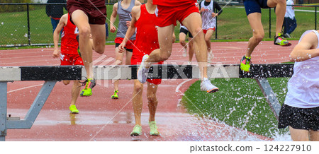 Competitors Leap Over Hurdles During a Wet Track Event at a Spring Athletic Meet in a Local Stadium 124227910