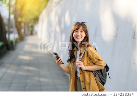Traveler young asian woman in her 30s explores Bangkok's vibrant scene with her phone. Discover the excitement and freedom of solo adventures. 124228384