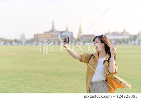 Traveler asian woman in her 30s explores the Grand Palace with a local guide. Uncover hidden gems and immerse yourself in Thai culture with her adventure. 124228385