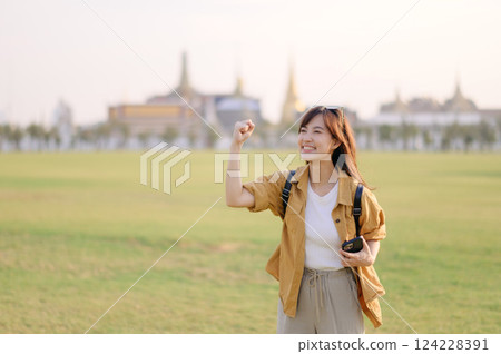 Traveler asian woman in her 30s navigates the bustling grounds of Wat Pra Kaew. Technology helps her translate signs and connect with locals, but it's the joy of exploration that fills her with 124228391