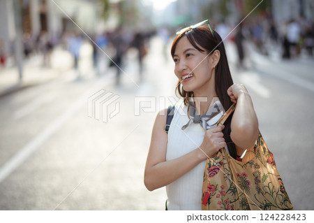 Casual urban life in Japan, Asian woman with a tote bag, smiling on a snowy sidewalk, Copy space for your personalized message. 124228423