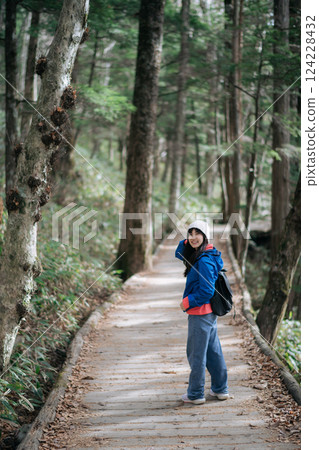 Serene solo trek, Asian woman in blue jacket enjoys Japan's November. A portrait of fall's elegance, happiness, and vibrant nature by the water. Serene solo trek, Asian woman in blue jacket enjoys Japan's November. A portrait of fall's elegance, happiness, and vibrant nature by the water. 124228432