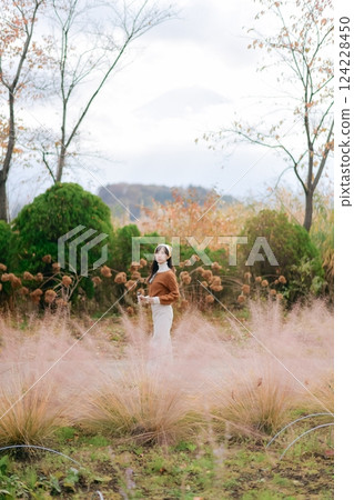 Asian woman in casual dress revels in the beauty of fall, adorned in a lovely coat. A joyful portrait amid nature's colorful backdrop, radiating cheer and happiness. 124228450
