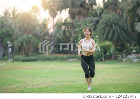 pretty asian woman jogger running in green nature public park. 124228472