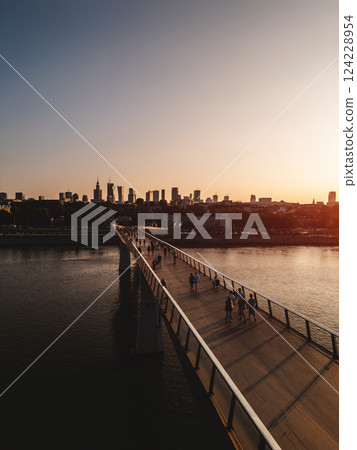 newly built pedestrian and bicycle modern bridge over Vistula river at sunset, downtown financial district and contemporary architecture of Warsaw city skyline, aerial top view newly built pedestrian and bicycle modern bridge over Vistula river at sunset, downtown financial district and contemporary architecture of Warsaw city skyline, aerial top view 124228954