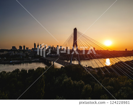 skyline of Warsaw city with downtown financial district and modern cable bridge over Vistula river at sunset, modern skyscrapers at background, aerial top view  124228981