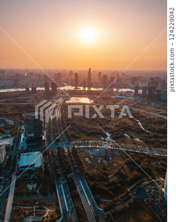 beautiful sunset over Ho Chi Minh city skyline and Saigon river, green tropical park and financial downtown district with tall skyscraper towers, Vietnam aerial drone view 124229042