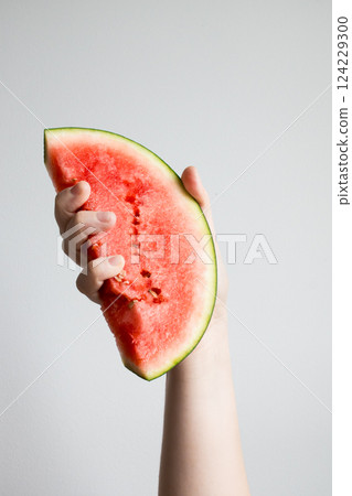 Hand holding juicy watermelon slice against white background Hand holding juicy watermelon slice against white background 124229300