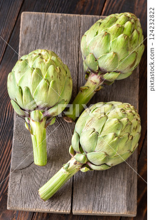Fresh raw artichokes on vintage cutting board with rustic wooden background texture 124232822