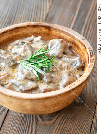 Hearty beef stroganoff in rustic bowl, garnished with fresh aromatic rosemary 124232826