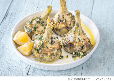 Four Roman-style artichokes served on white plate, tender and beautifully seasoned 124232835