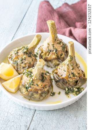 Four Roman-style artichokes served on white plate, tender and beautifully seasoned Four Roman-style artichokes served on white plate, tender and beautifully seasoned 124232837