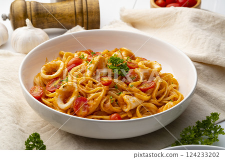Linguine pasta with squid and cherry tomato in tomato sauce in white plate Linguine pasta with squid and cherry tomato in tomato sauce in white plate 124233202