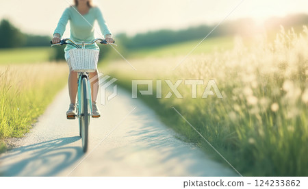 person riding bicycle on sunny path surrounded by greenery, enjoying peaceful moment in nature. soft light creates serene atmosphere 124233862