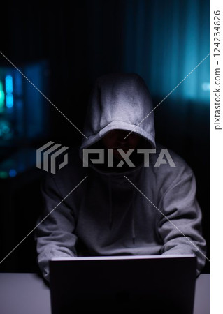 Hacker using the computer. Man in a hoodie breaks the access to steal information and infects computers and systems Hacker using the computer. Man in a hoodie breaks the access to steal information and infects computers and systems 124234826