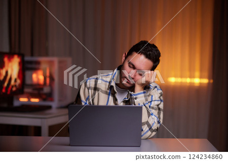 Focused young man wearing glasses using laptop, typing on keyboard 124234860