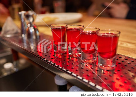 Bartender pouring and serving alcoholic drinks at bar 124235116