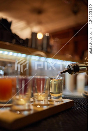 Bartender pouring and serving alcoholic drinks at bar 124235120