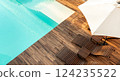 Turquoise swimming pool with wooden deck, lounge chairs, and umbrella in a modern outdoor setting 124235522