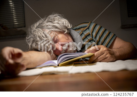 Elderly man dozing off while reading a book 124235767