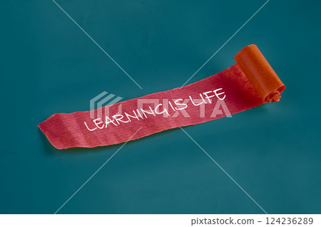 A vibrant background showcases a rolled ribbon with the words Learning is life, emphasizing the importance of education and personal development 124236289