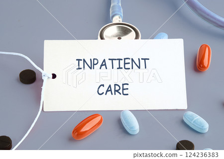 A tag labeled inpatient care rests on a gray surface surrounded by different types of medical pills and a stethoscope A tag labeled inpatient care rests on a gray surface surrounded by different types of medical pills and a stethoscope 124236383