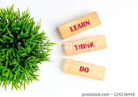 Wooden blocks displaying the words learn, think, and do emphasize key concepts in education and business, surrounded by greenery 124236448