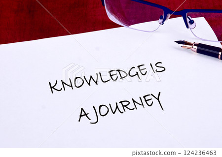 A handwritten note emphasizes that knowledge is a journey, surrounded by business tools like glasses and a fountain pen, promoting education in finance A handwritten note emphasizes that knowledge is a journey, surrounded by business tools like glasses and a fountain pen, promoting education in finance 124236463