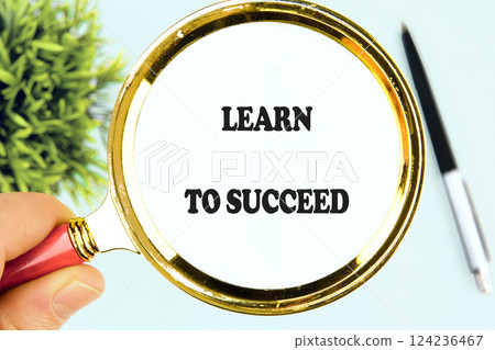 A hand holds a magnifying glass over a message emphasizing learning to succeed, symbolizing the importance of education in business and finance 124236467