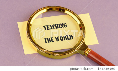 A magnifying glass emphasizes the words teaching the world on a pale surface, illustrating a dedication to global education concepts 124236560