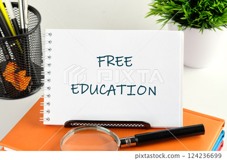 A desk setting showcasing a notepad with the phrase free education, emphasizing the importance of accessible learning materials for all A desk setting showcasing a notepad with the phrase free education, emphasizing the importance of accessible learning materials for all 124236699