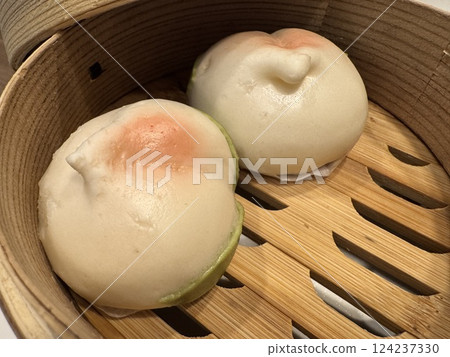 A bamboo steamer for steaming food containing peach buns 124237330