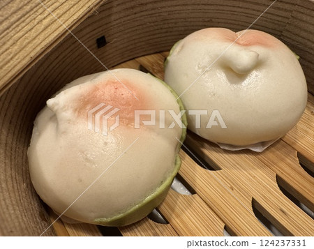 A bamboo steamer for steaming food containing peach buns 124237331
