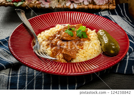 Chunky beef stew with savory sauce, served with bulgur groats. 124238842