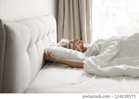 Smiling older woman lie on back sleeping in large bed 124239573