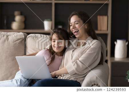 Happy young mother little daughter laughing at movie on notebook 124239593