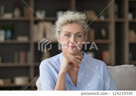 Headshot portrait senior woman posing on sofa looking at camera 124239595
