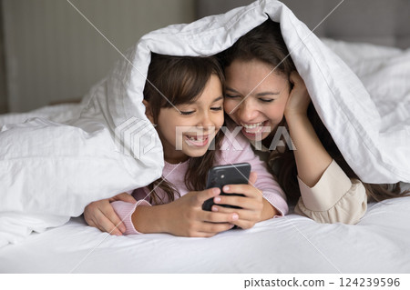 Young mommy little daughter lying on bed using mobile phone 124239596