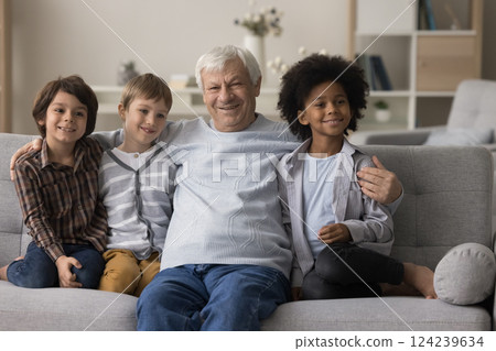 Older grandpa cuddle on sofa with 6-7 years old grandsons Older grandpa cuddle on sofa with 6-7 years old grandsons 124239634