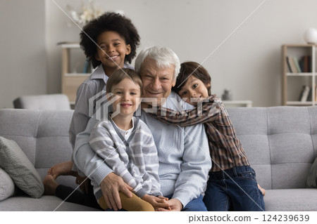 Senior grandfather sit on couch in hugs of little grandsons Senior grandfather sit on couch in hugs of little grandsons 124239639