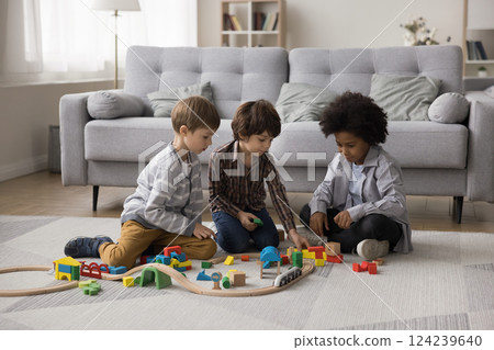 Multiethnic little boys playing on floor with railway construction set Multiethnic little boys playing on floor with railway construction set 124239640